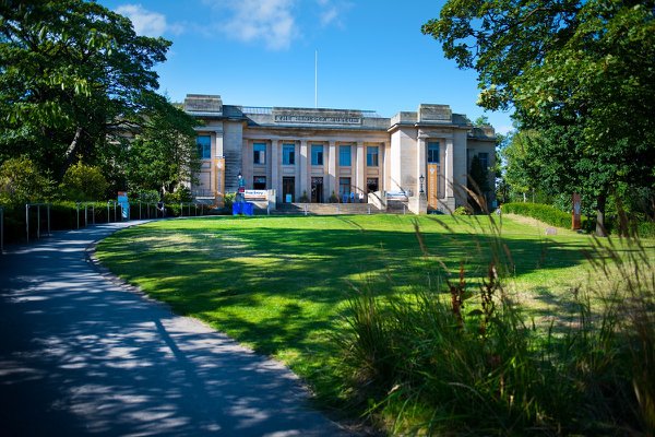Exterior view of the Great North Museum in Newcastle, including a large lawn and trees in summer foliage