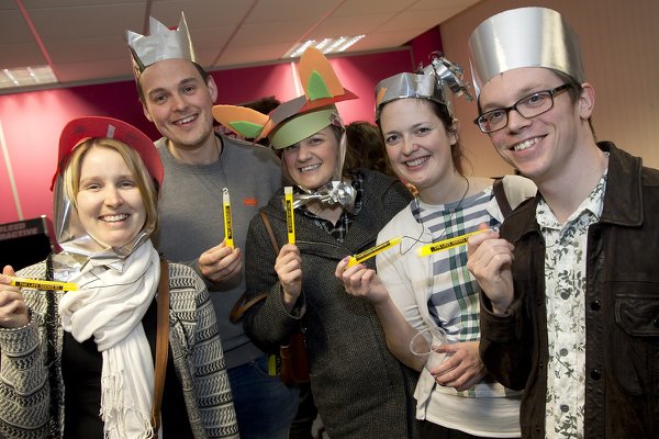  A group of five people wearing fancy craft hats and holding yellow glow sticks. They are smiling at the camera