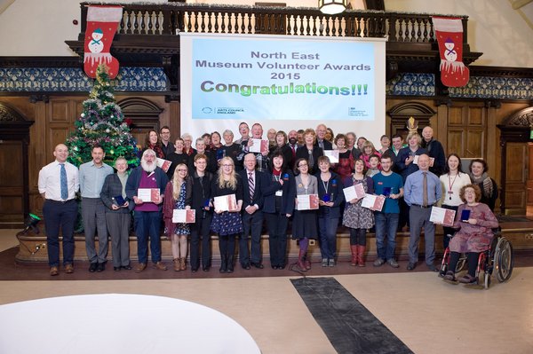  A large group of volunteers holding certificates at an awards ceremony at the Discovery Museum, Newcastle upon Tyne