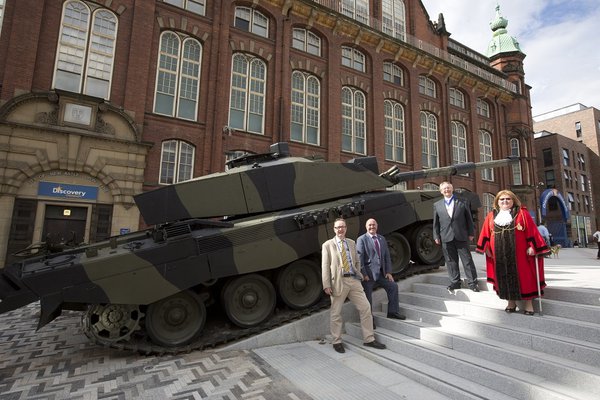 Dignitaries stand beside a large green and black battle tank outside the Discovery Museum in Newcastle upon Tyne
